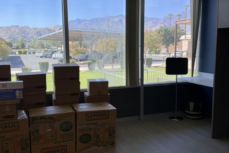 Photo of moving boxes stacked near the window in an office.