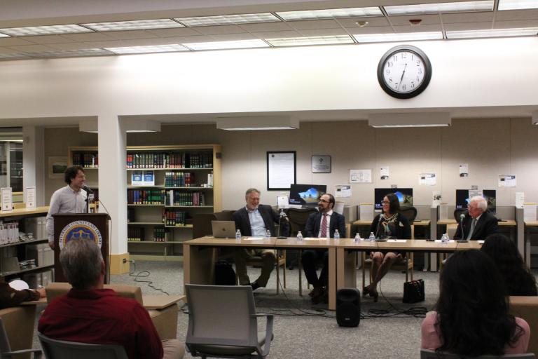 A library staff member moderates the discussion of four panelists.