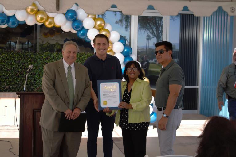 Board President John Boyd, a representative of Assemblymember Greg Wallis, Deputy Chief of Staff Patricia Cooper, and County Facilities Management Director Vince Izaguirre posing with a certificate from the California State Assembly.