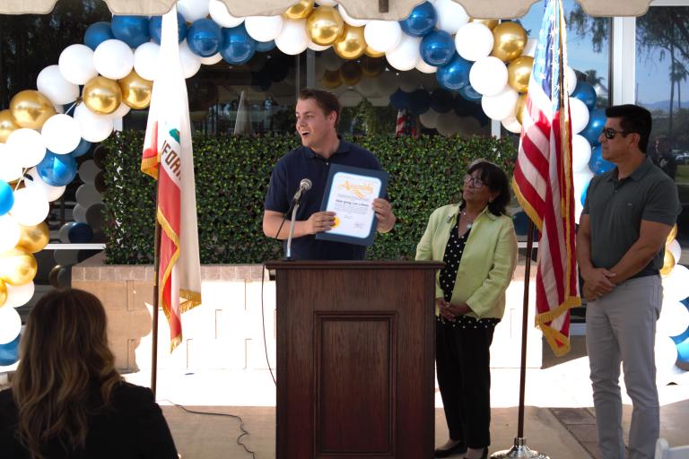 A representative of State Assemblymember Greg Wallis presenting a certificate from the California State Assembly.