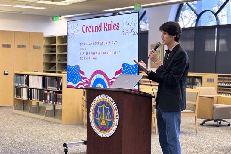 Library Assistant Matthew Palacios emcees Trivia Night.