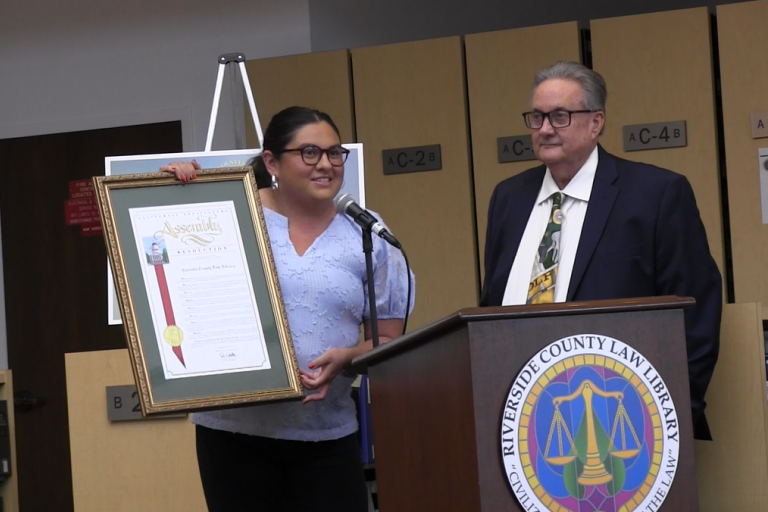 Field Representative Toni Rosales from the office of State Assemblywoman Leticia Castillo presents an Assembly resolution commemorating the Law Library.