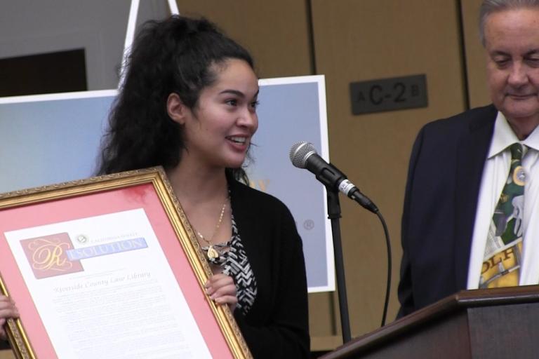 District Representative Lina Cardenas from the office of State Senator Sabrina Cervantes presents a Senate resolution commemorating the Law Library.
