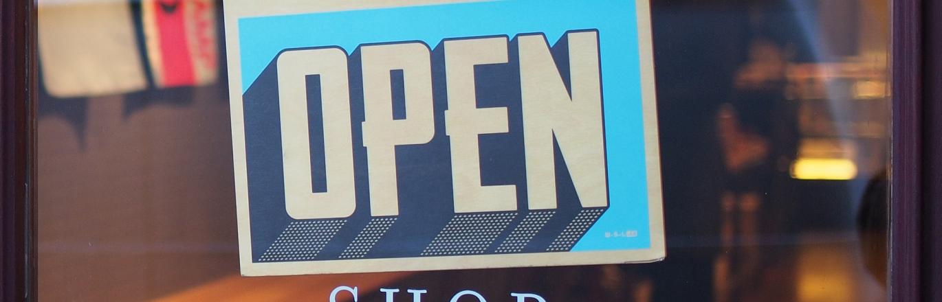open sign in blue lettering on the glass door of a shop