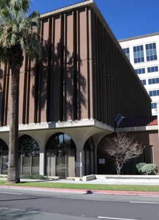 outside pic of the law library- a 3 story brown brick building with 2 palm trees out front