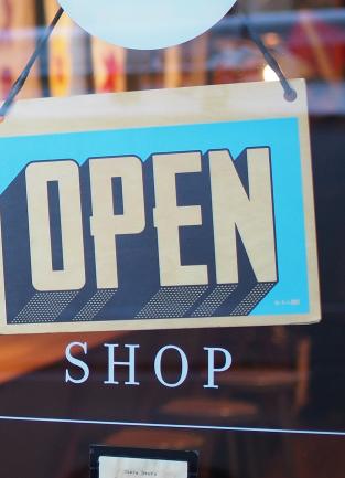 open sign in blue lettering on the glass door of a shop